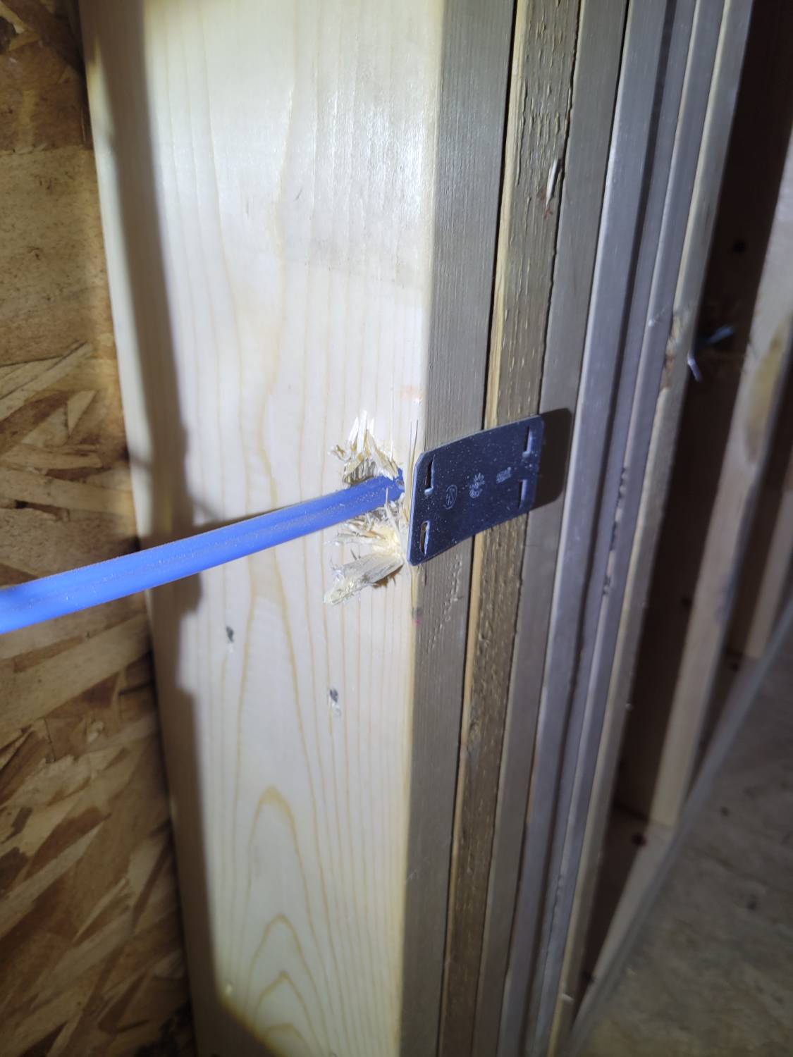 An electrical conductor shown near the edge of the framing, but noted to correctly have a safety plate by the home inspector.