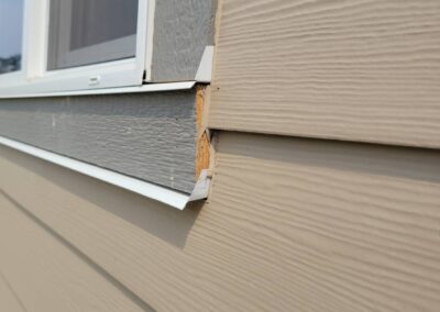 Close-up of an exterior siding installation defect on a newly built home, showing exposed wood.