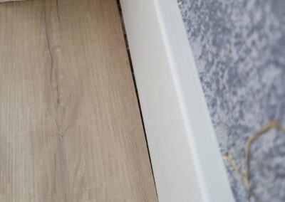 Gap between baseboard and flooring in a new home, indicating poor finishing by the contractor.
