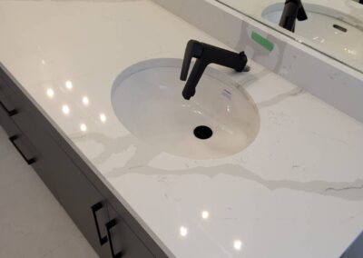 Double vanity bathroom with quartz countertop under inspection, marked for incomplete installation of the faucet.