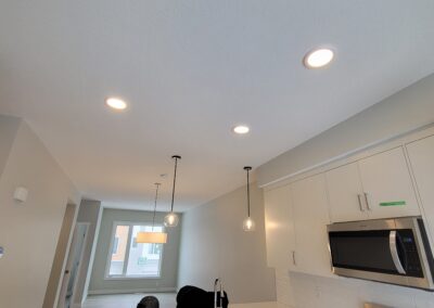 New construction kitchen with recessed lighting and pendant fixtures, undergoing final inspection.